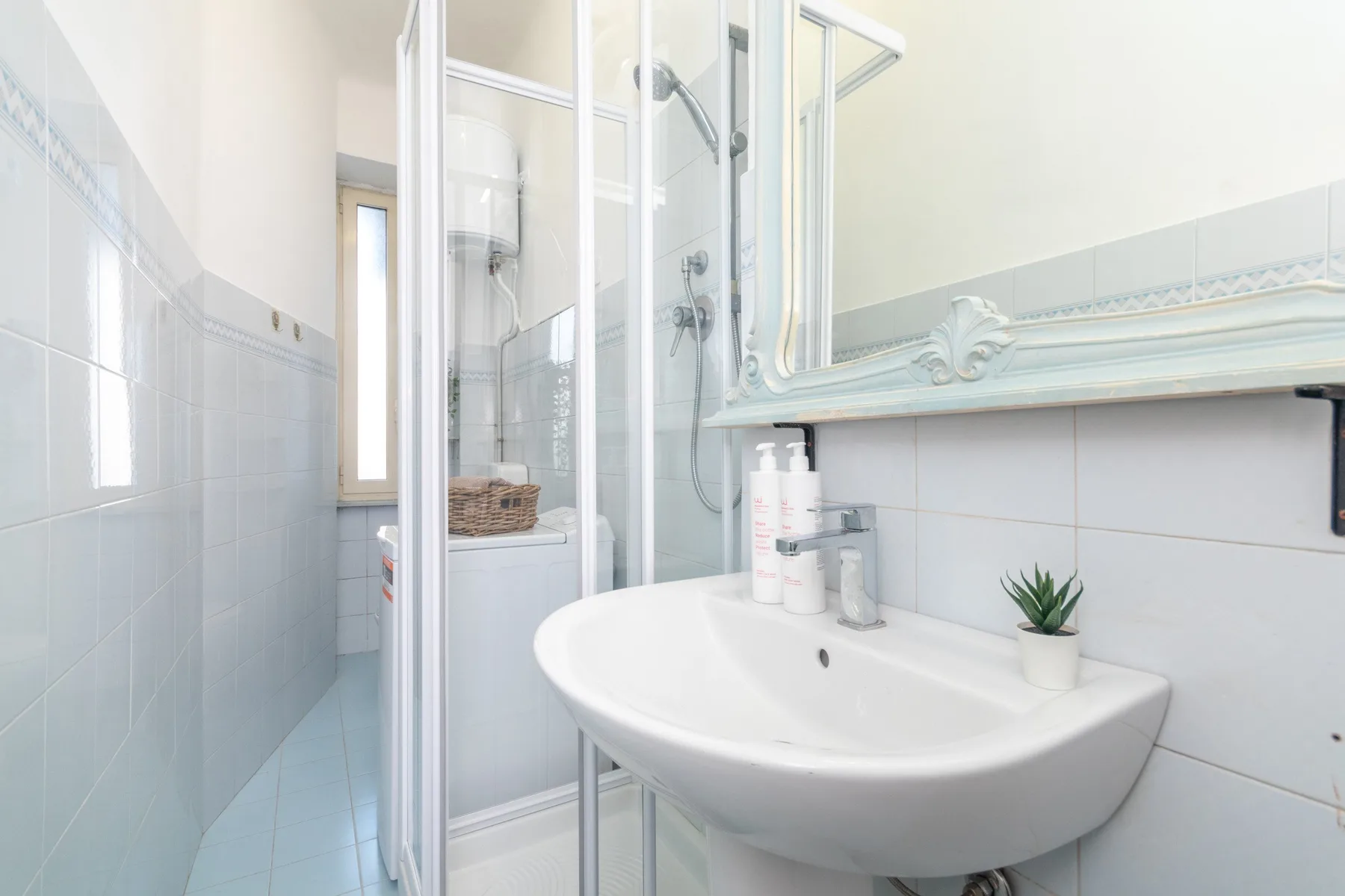 Un baño luminoso con un lavabo blanco y una ducha de vidrio.