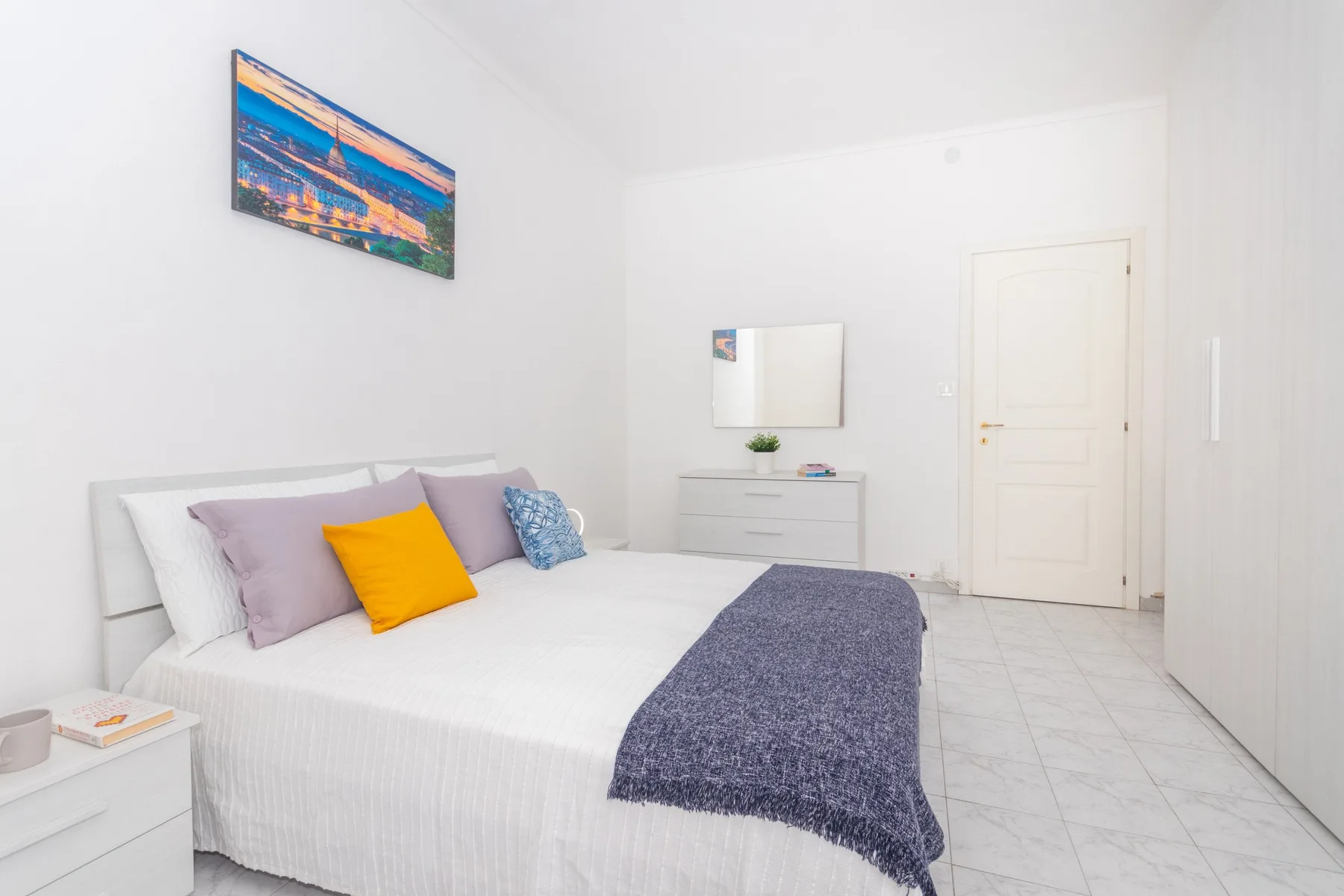 Un dormitorio luminoso con una cama bien hecha y almohadas de colores.