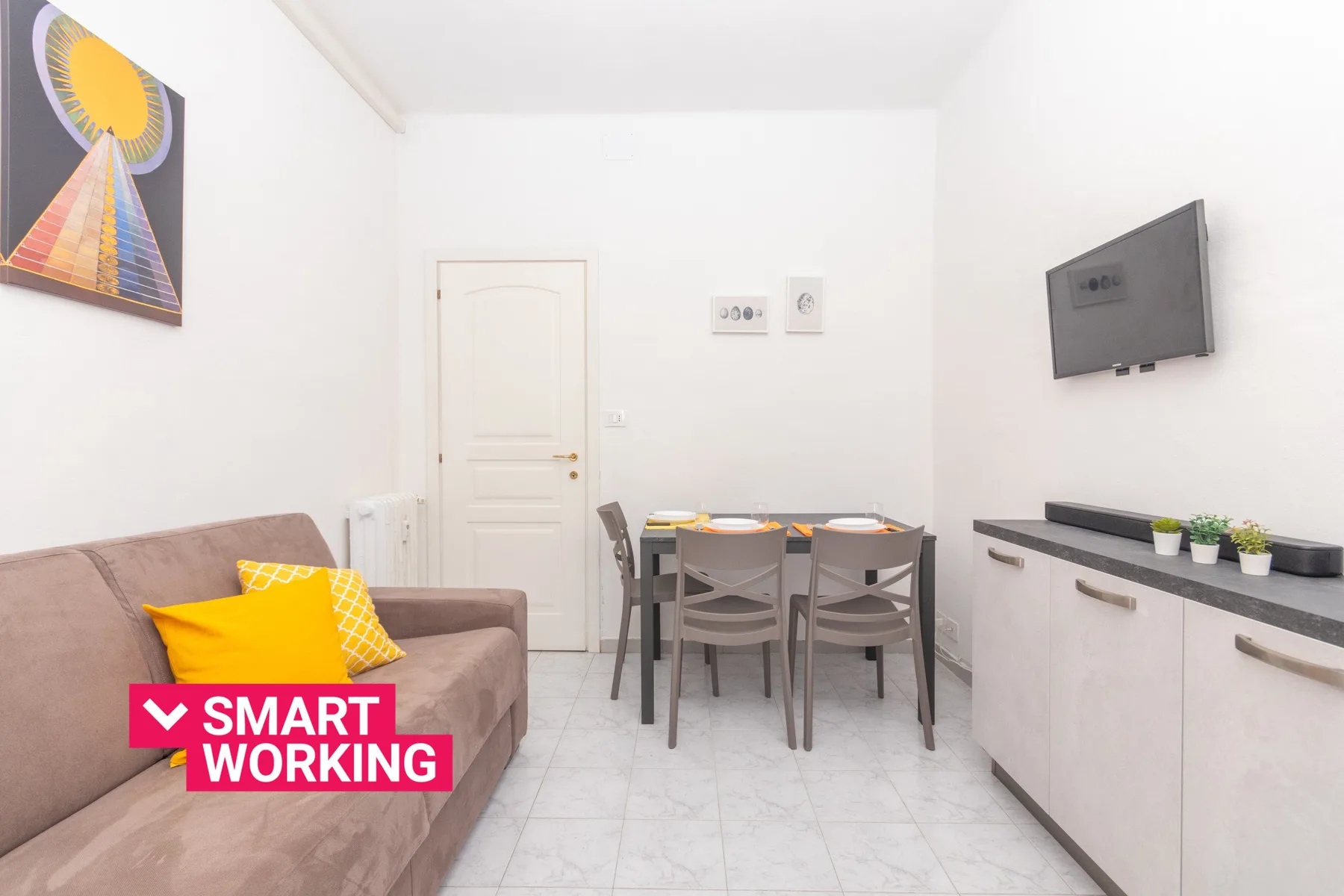 Un comedor y sala luminosos con una mesa, asientos y un televisor montado en la pared.