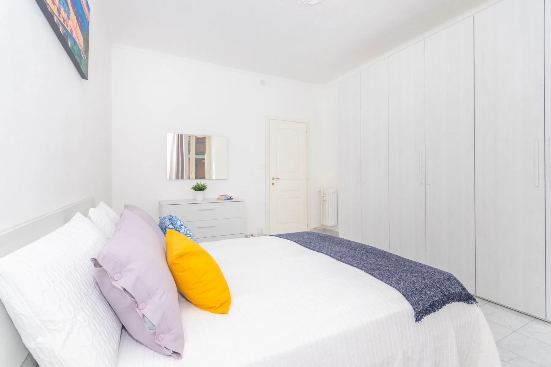 Un dormitorio luminoso con una cama bien tendida y armarios empotrados.