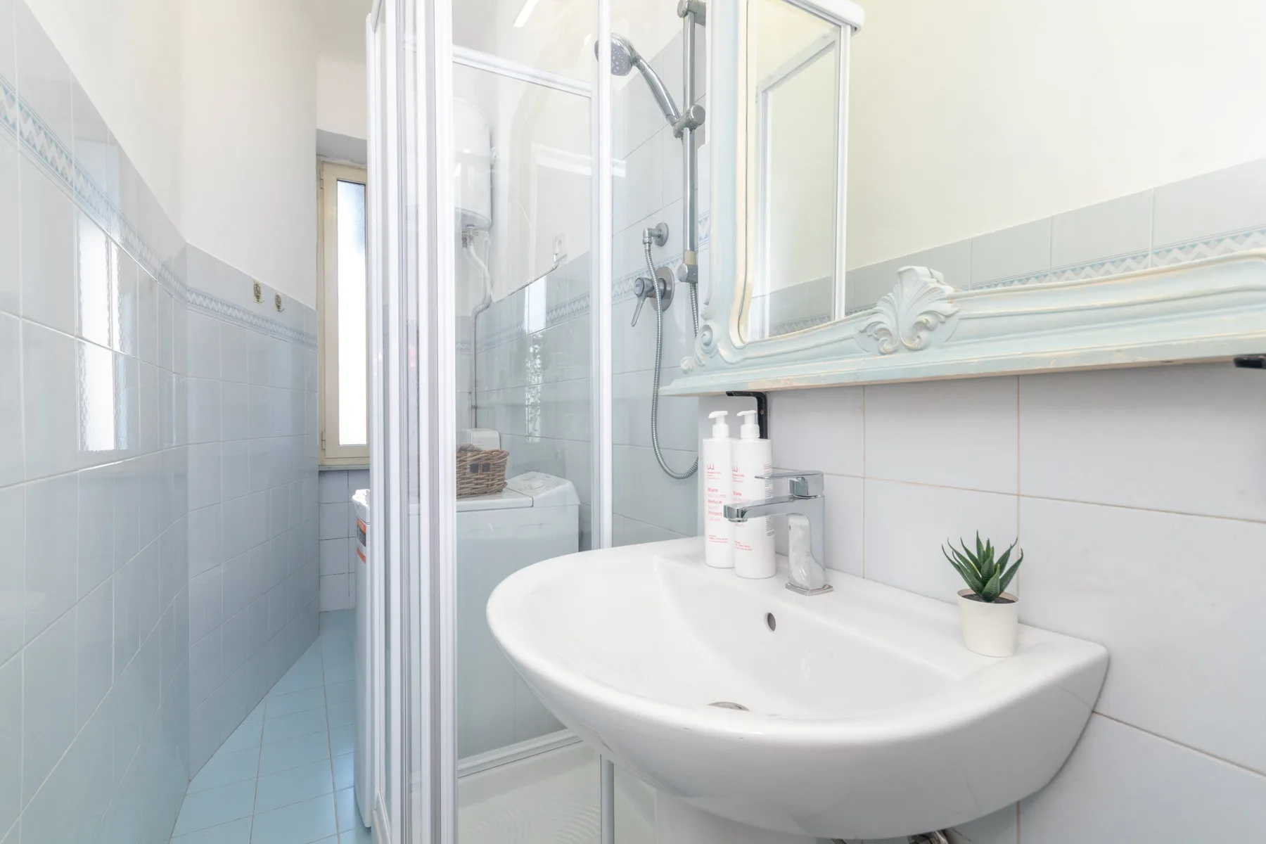 Un baño luminoso con lavabo, espejo y ducha de cristal.