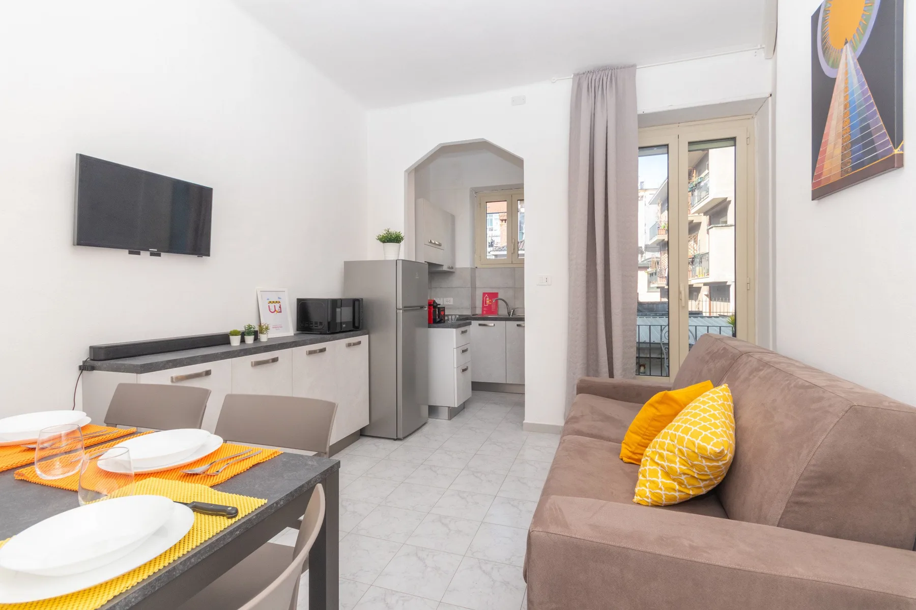 Una luminosa sala-comedor con sofá, mesa y cocina compacta.
