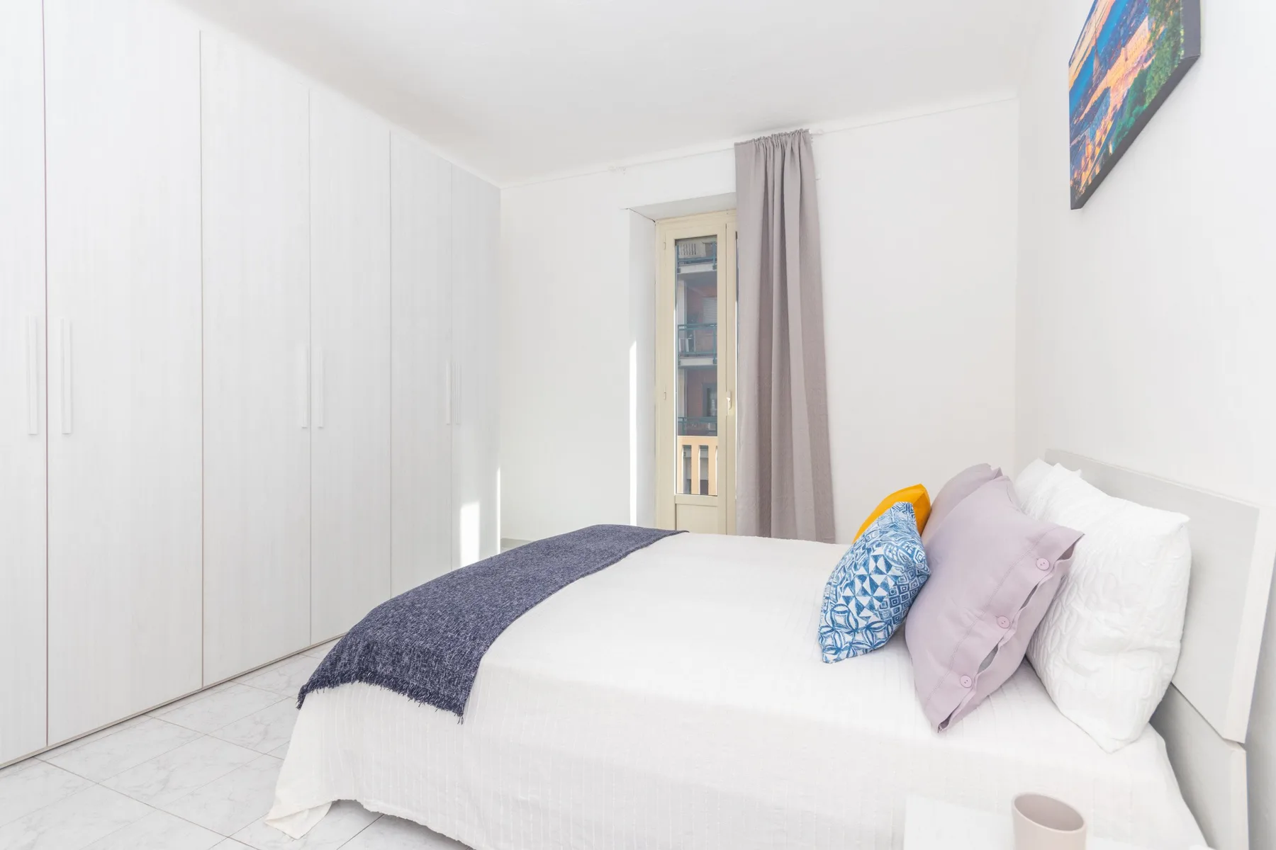 Un dormitorio luminoso con una cama, ropa de cama blanca y armarios empotrados.