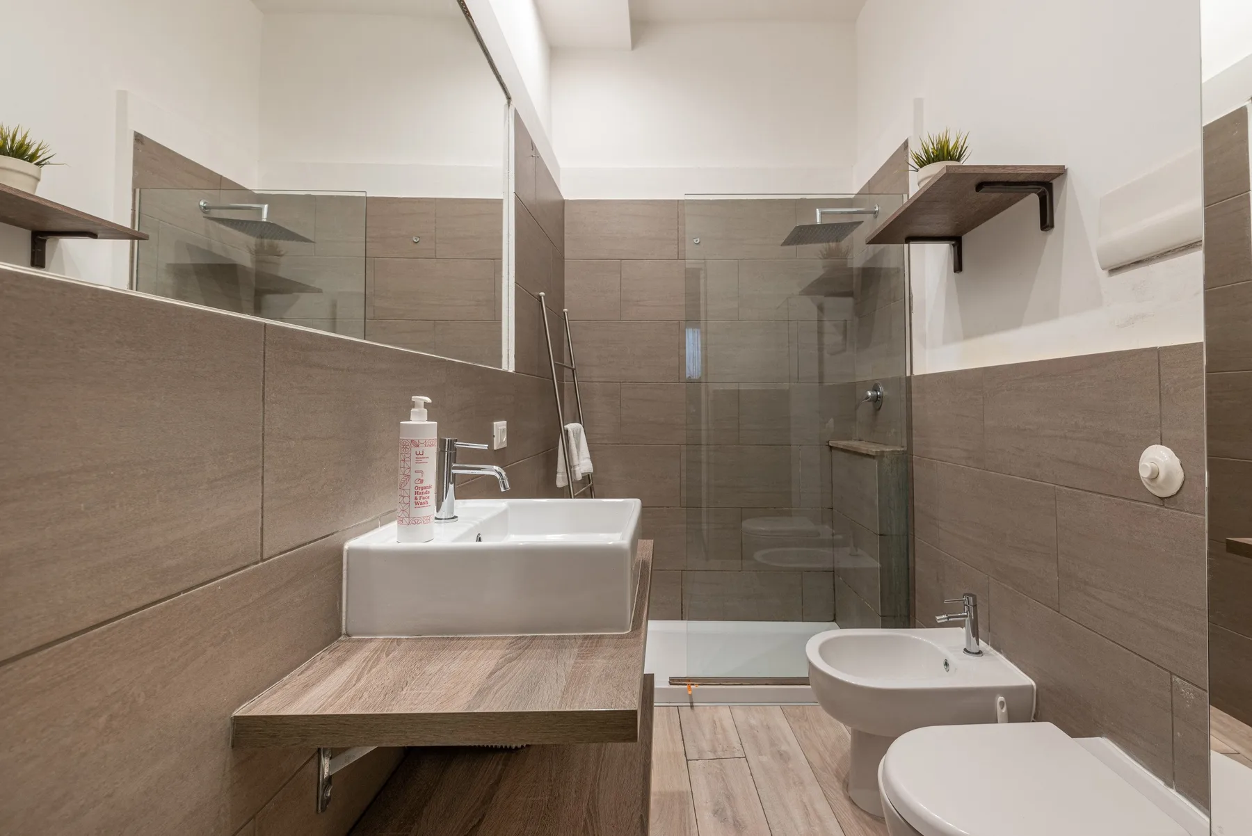 A modern bathroom with a sink, shower, and toilet.