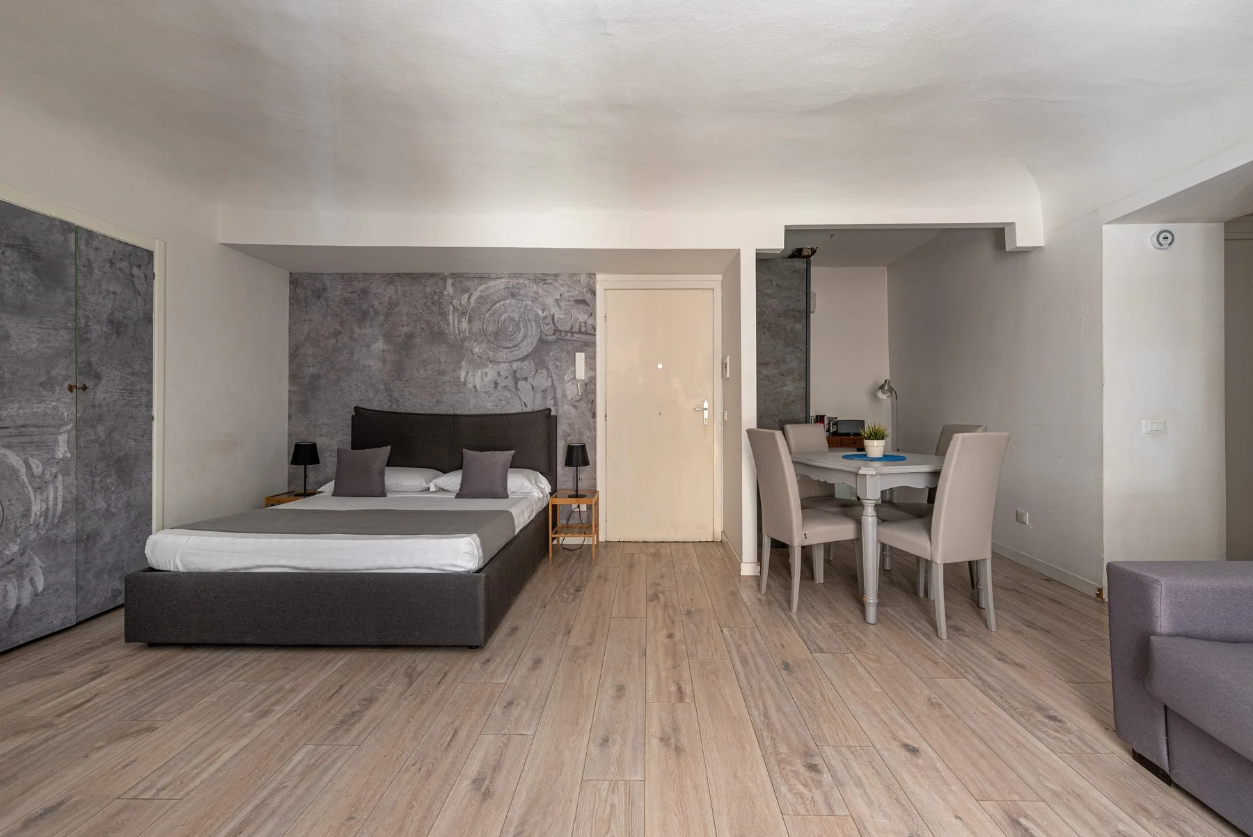 Un dormitorio y un comedor comparten un espacio abierto, con una cama y una mesa.