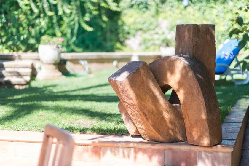 A garden sculpture sits on a low brick ledge beside a grassy lawn.