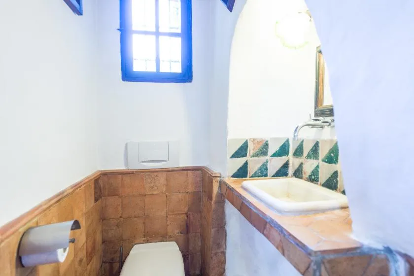 A tiled bathroom with a toilet and a built-in bathtub beneath an arched opening.
