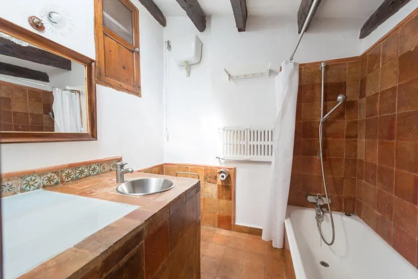 A bathroom with a tiled vanity and a bathtub behind a shower curtain.
