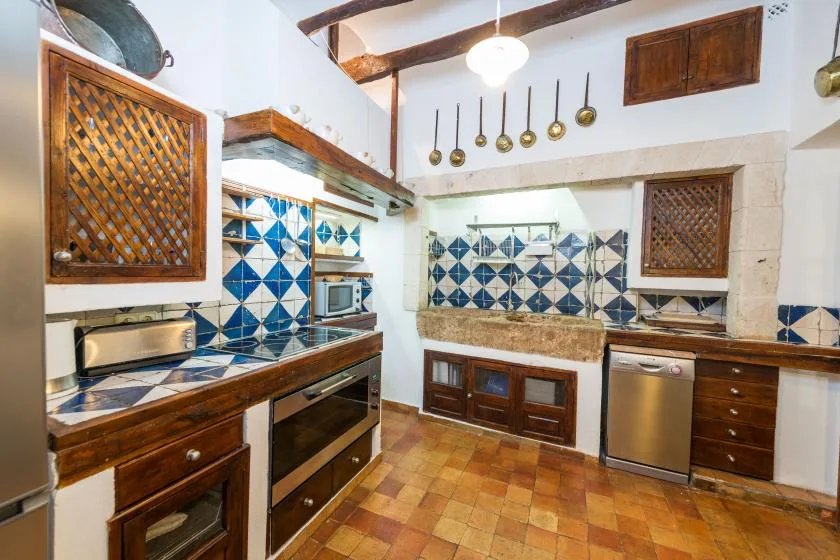 A kitchen with blue-and-white tiled counters and wooden cabinetry.