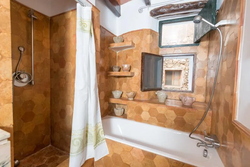 A tiled bathroom with a bathtub, shower, and small window.