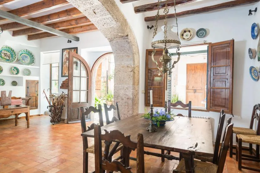 A dining room with a long wooden table beneath exposed ceiling beams.