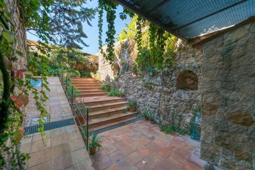 A tiled outdoor courtyard with steps rising beside vine-covered stone walls.