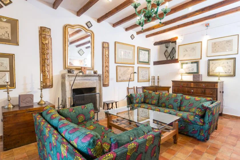 A living room with colorful patterned seating arranged around a glass coffee table.