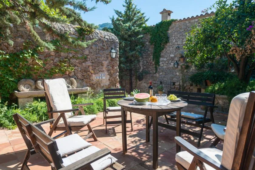 An outdoor patio with seating around a table beneath trees.