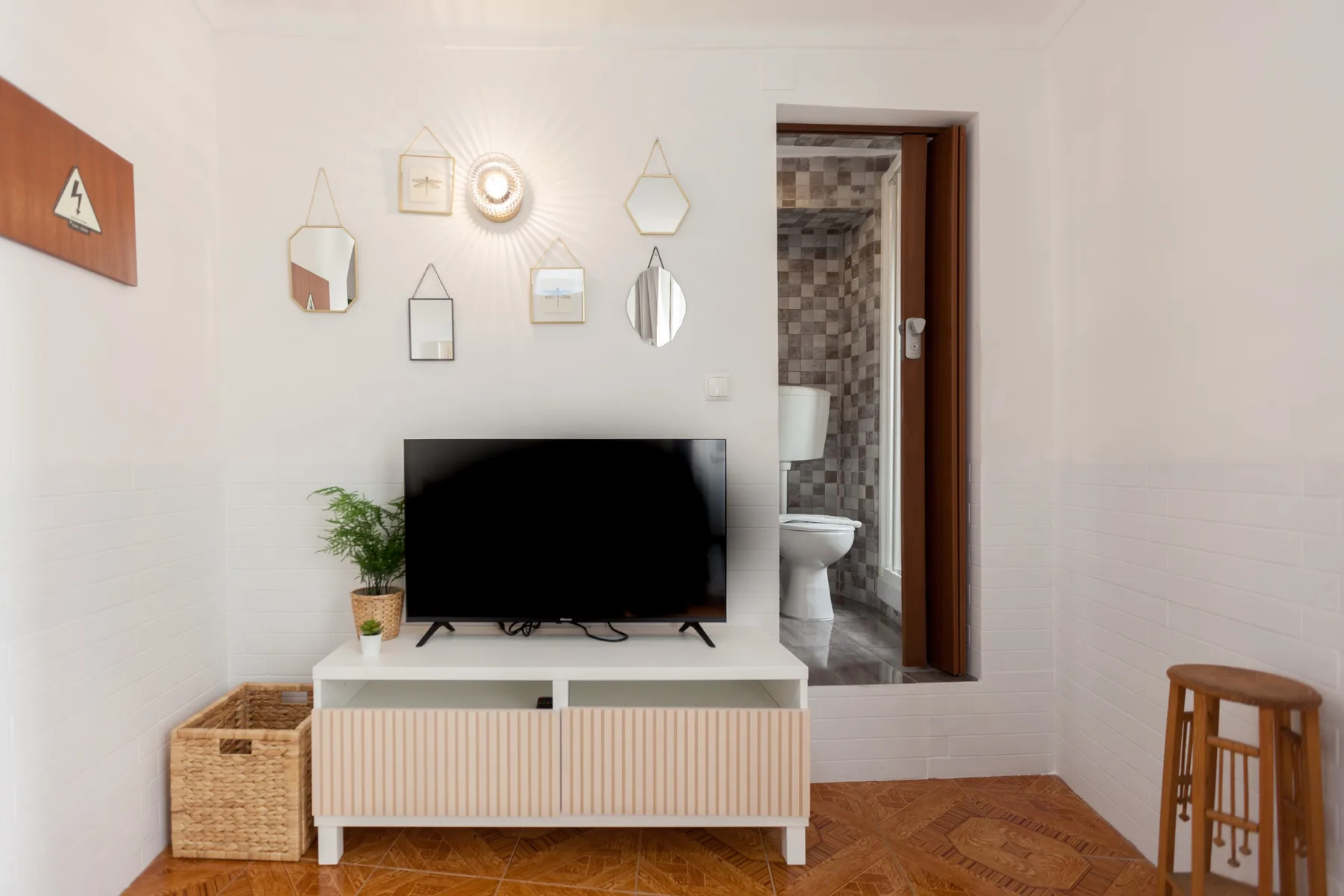 Una sala de estar con un televisor y una puerta al baño.