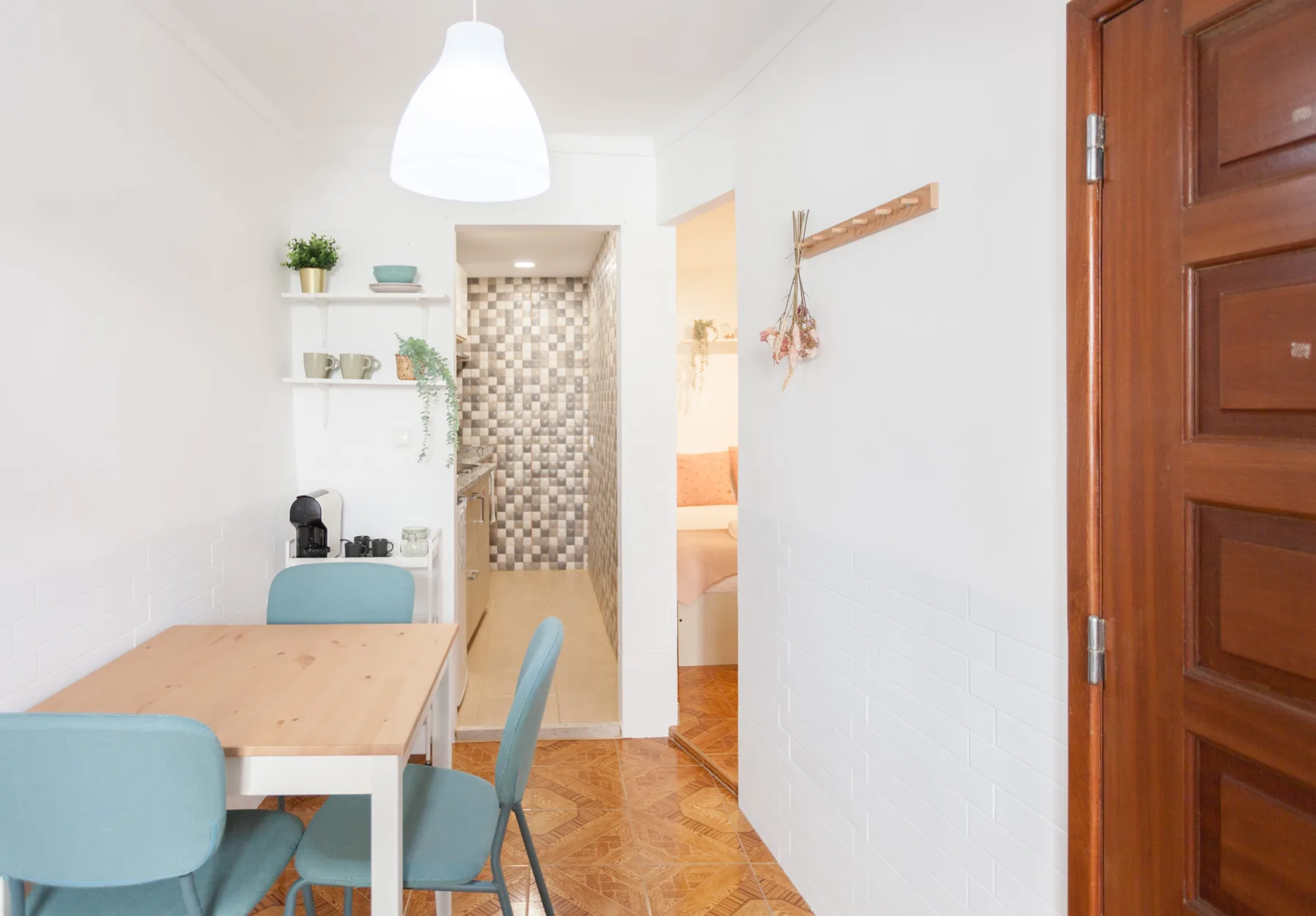 Comedor con una mesa de madera y asientos azules junto a un pasillo.