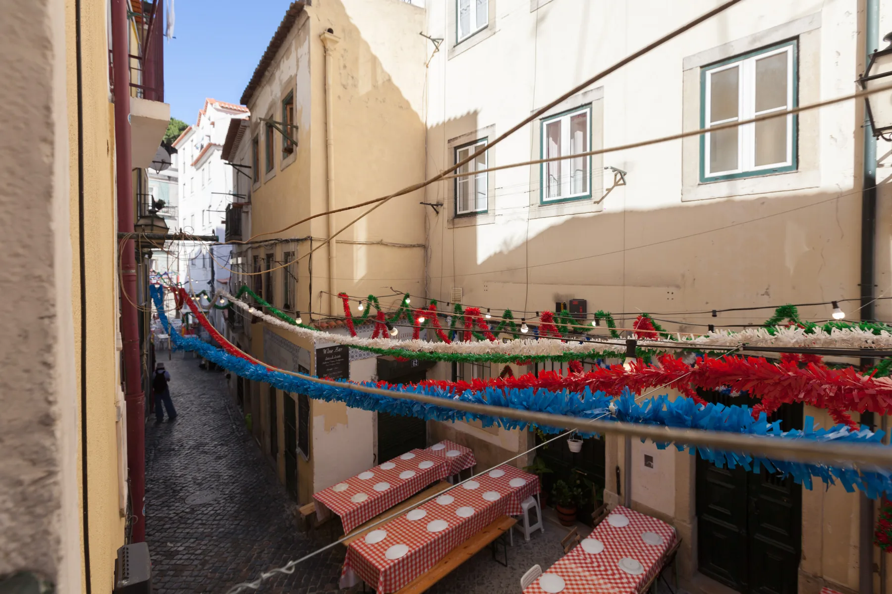 Una calle estrecha entre edificios, decorada con guirnaldas de colores en lo alto.