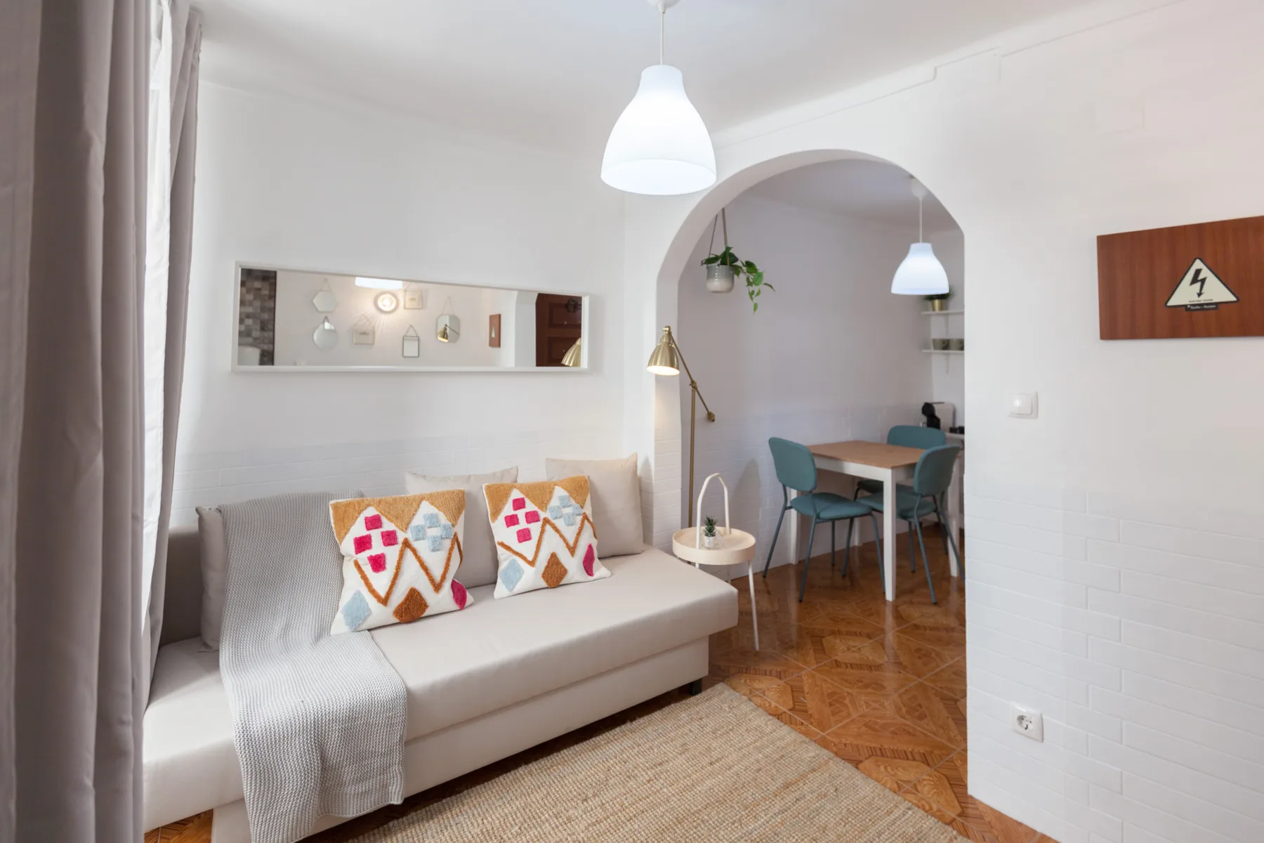 Una sala luminosa con asientos junto a un arco que da a un comedor.