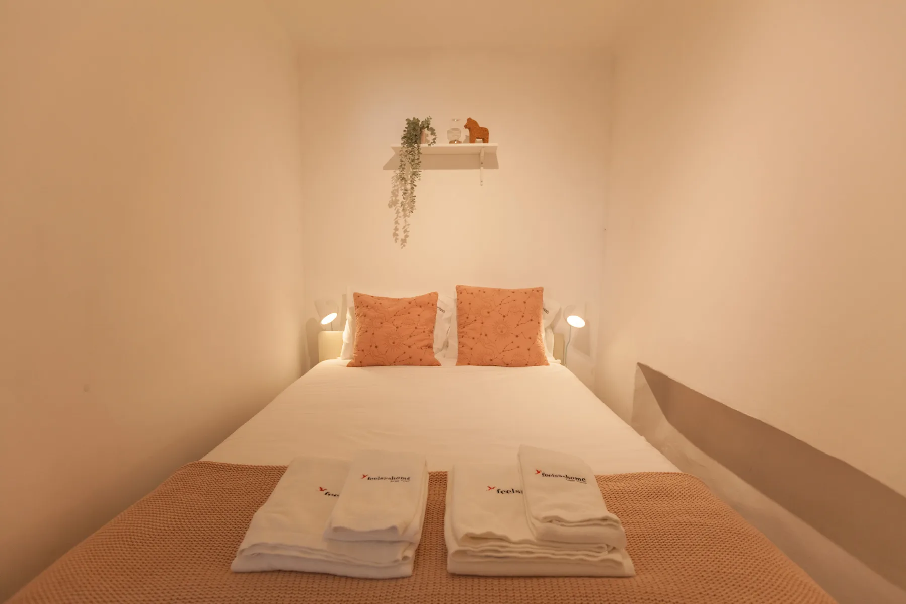 Un dormitorio con una cama tendida y toallas dobladas a los pies.