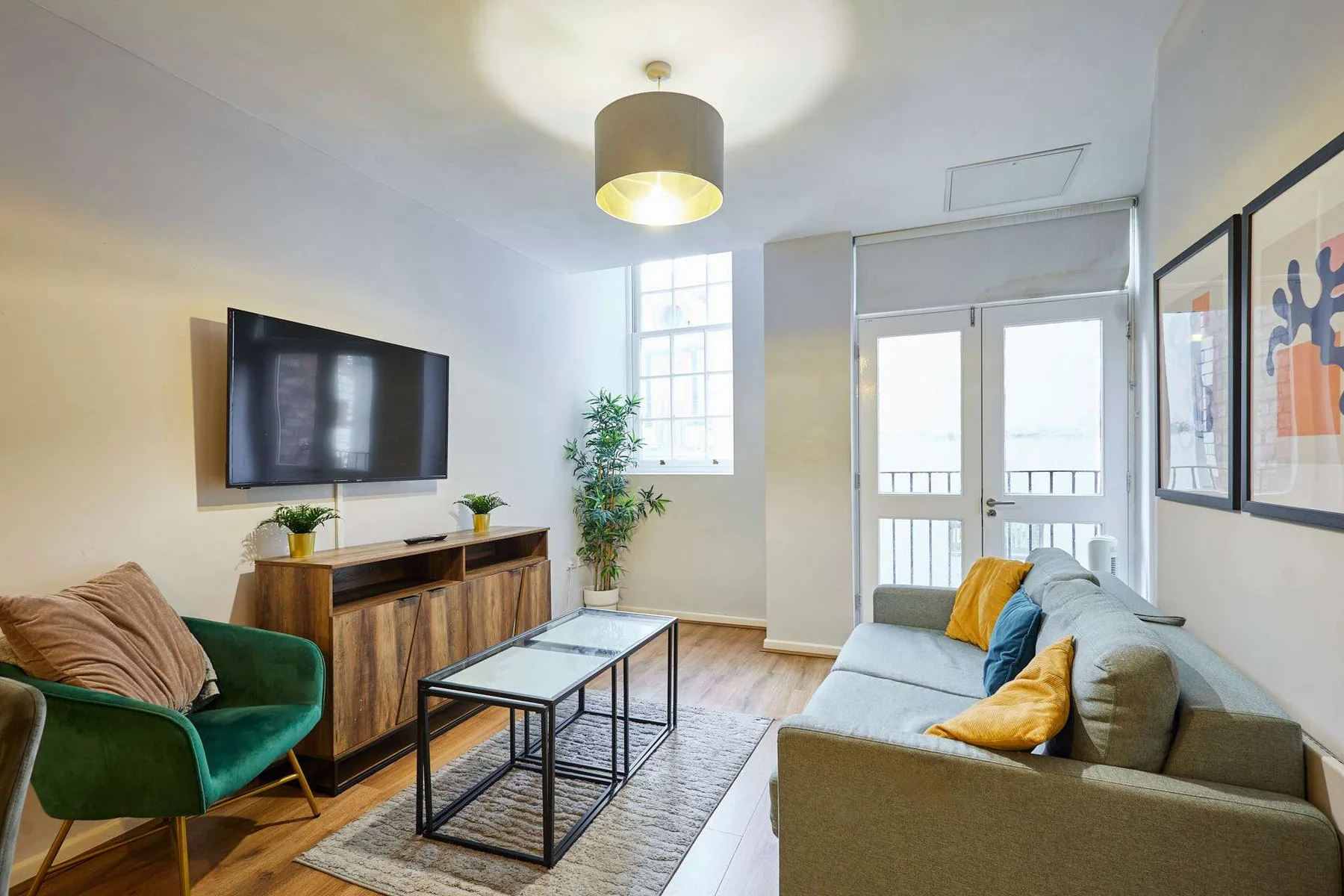 Una sala luminosa con asientos, un televisor y una mesa de centro de vidrio.