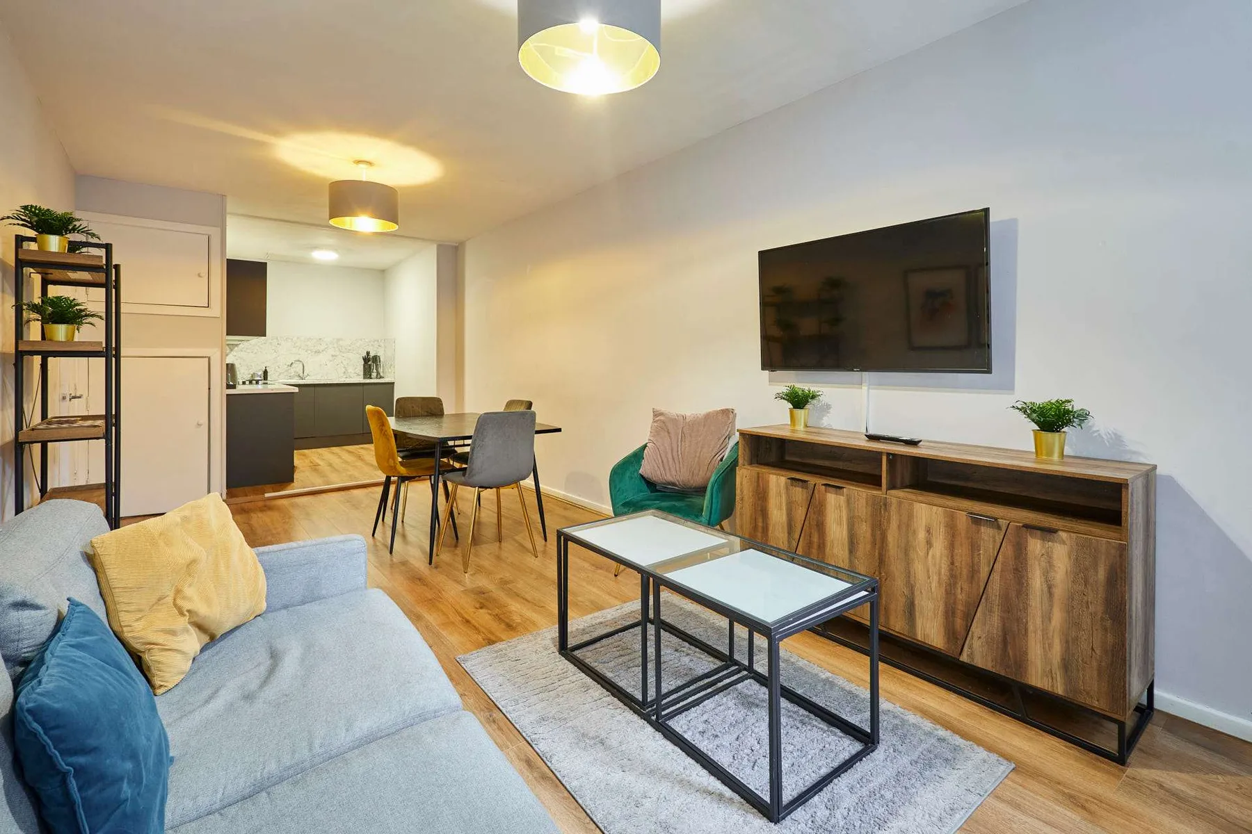 A living room with seating, coffee tables, and a television beside the dining area.