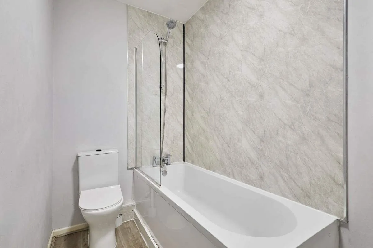A bathroom with a bathtub and wall-mounted shower.