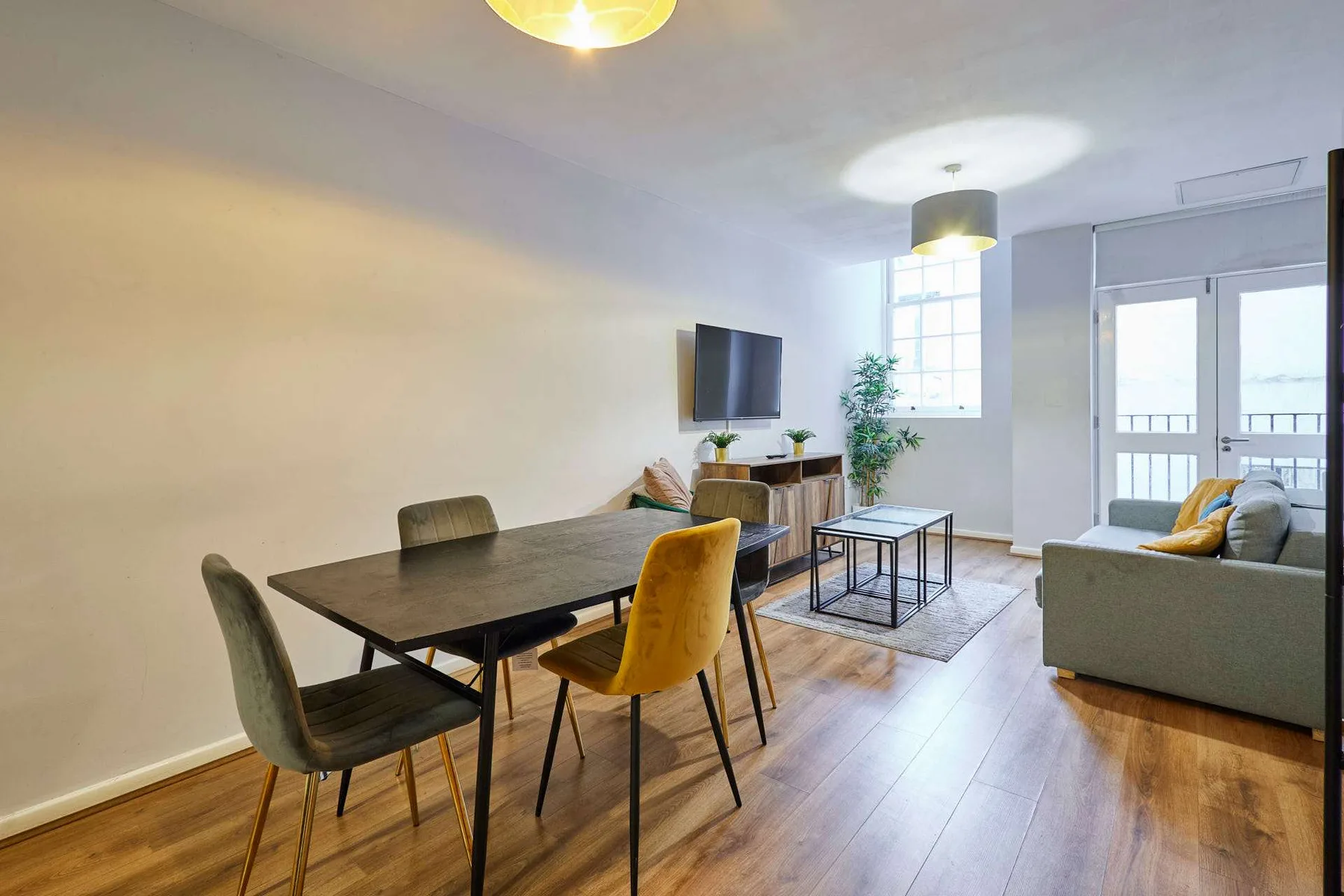 Una luminosa sala de estar y comedor con mesa, asientos y televisor.