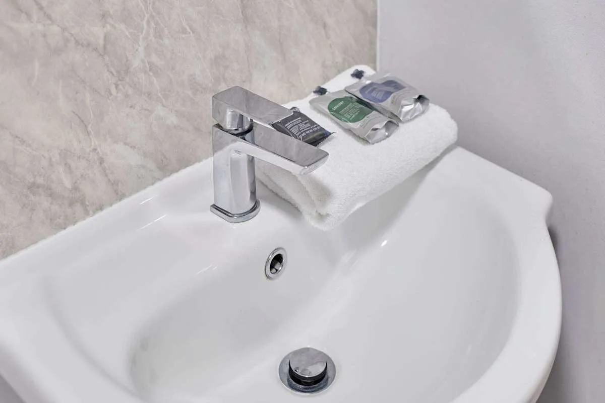 A bathroom sink with a chrome faucet and folded towels.