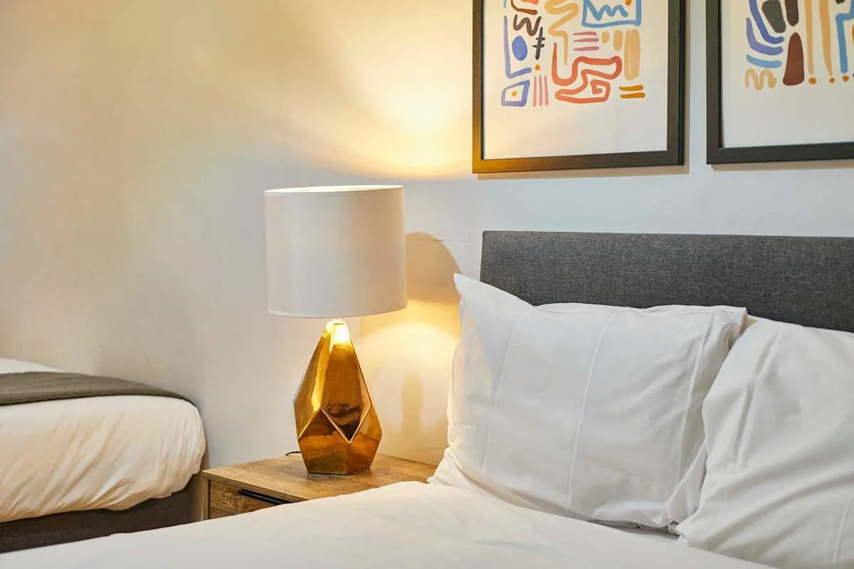 A bedroom with a bedside lamp and framed artwork above the bed.