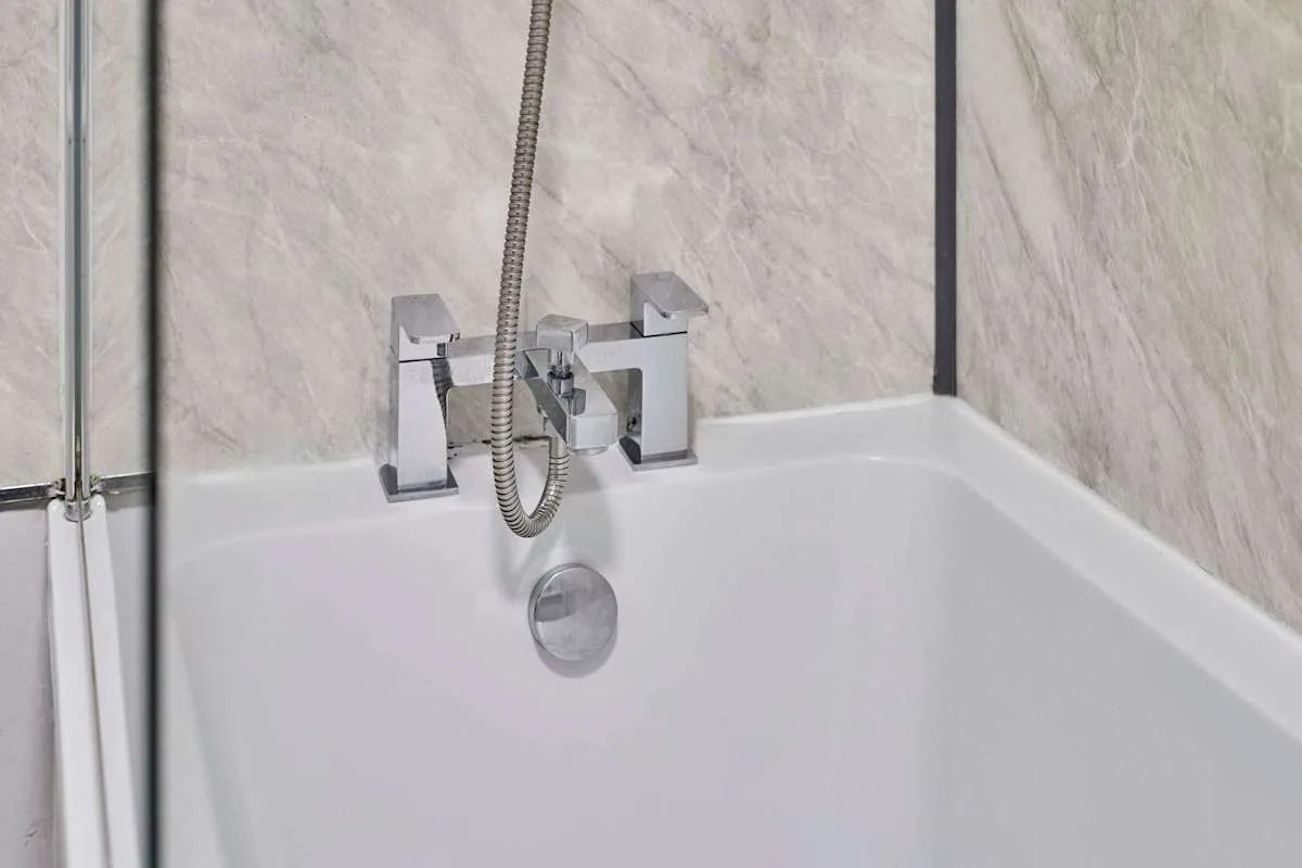 A bathtub with a wall-mounted faucet and handheld shower.