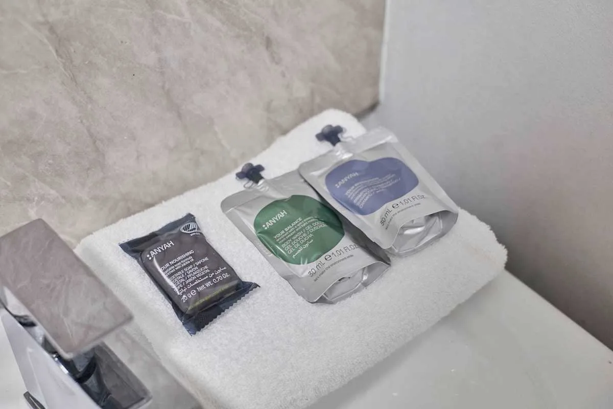 Bathroom toiletries are arranged on a folded white towel beside the sink.