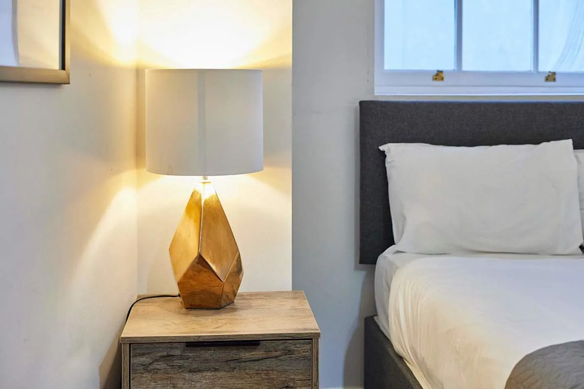 A bedroom with a bedside lamp beside a bed.
