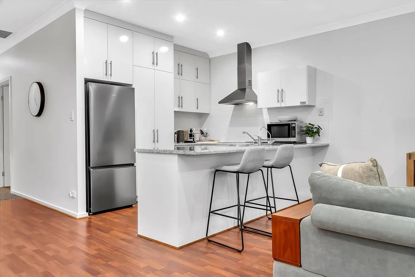 Open kitchen with a breakfast bar and seating beside a living area.