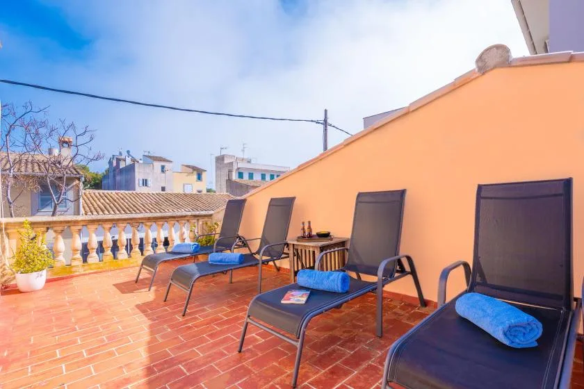 A sunny terrace with lounge seating and an orange wall.