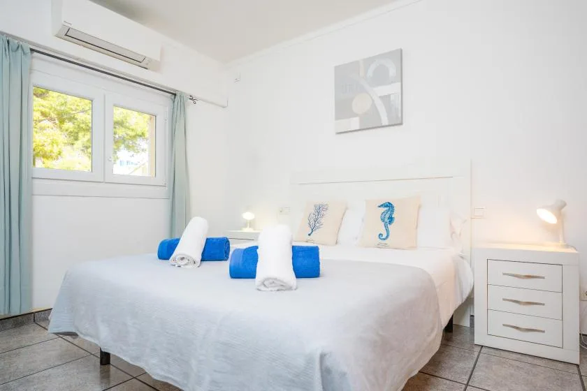 A bright bedroom with a neatly made bed and blue accents.