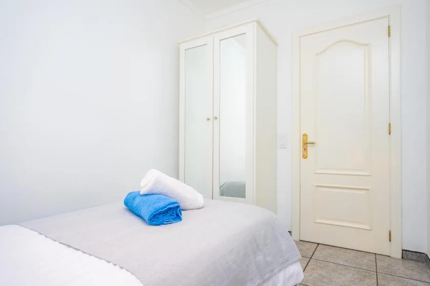 A bedroom with a neatly made bed and folded towels.