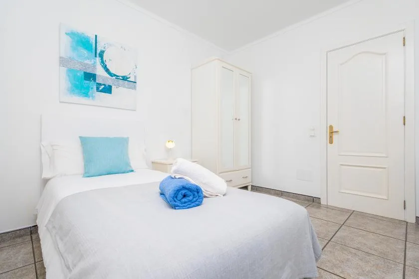 Bedroom with a neatly made bed and a blue towel.