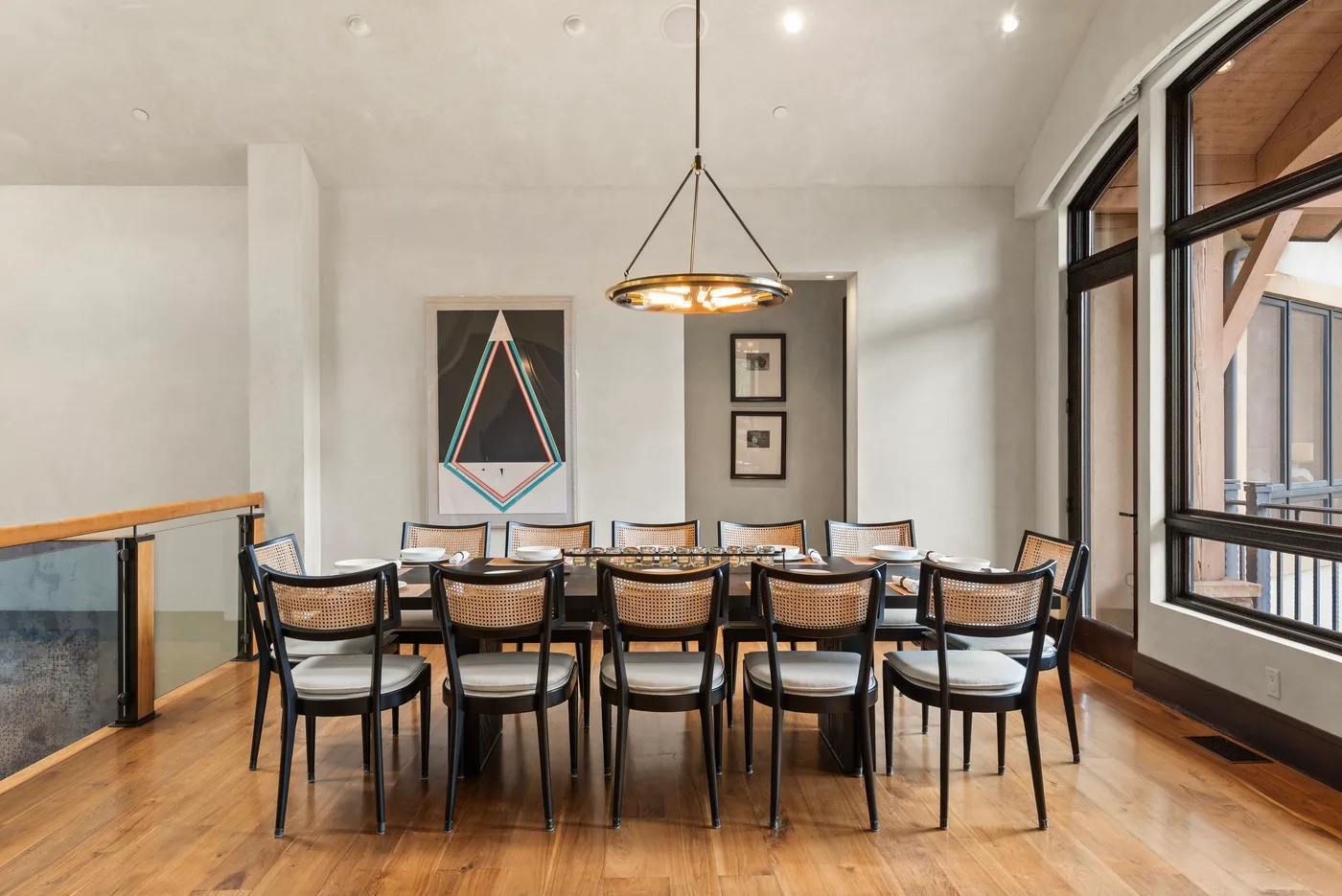 Un comedor con una mesa larga y sillas bajo una lámpara colgante.
