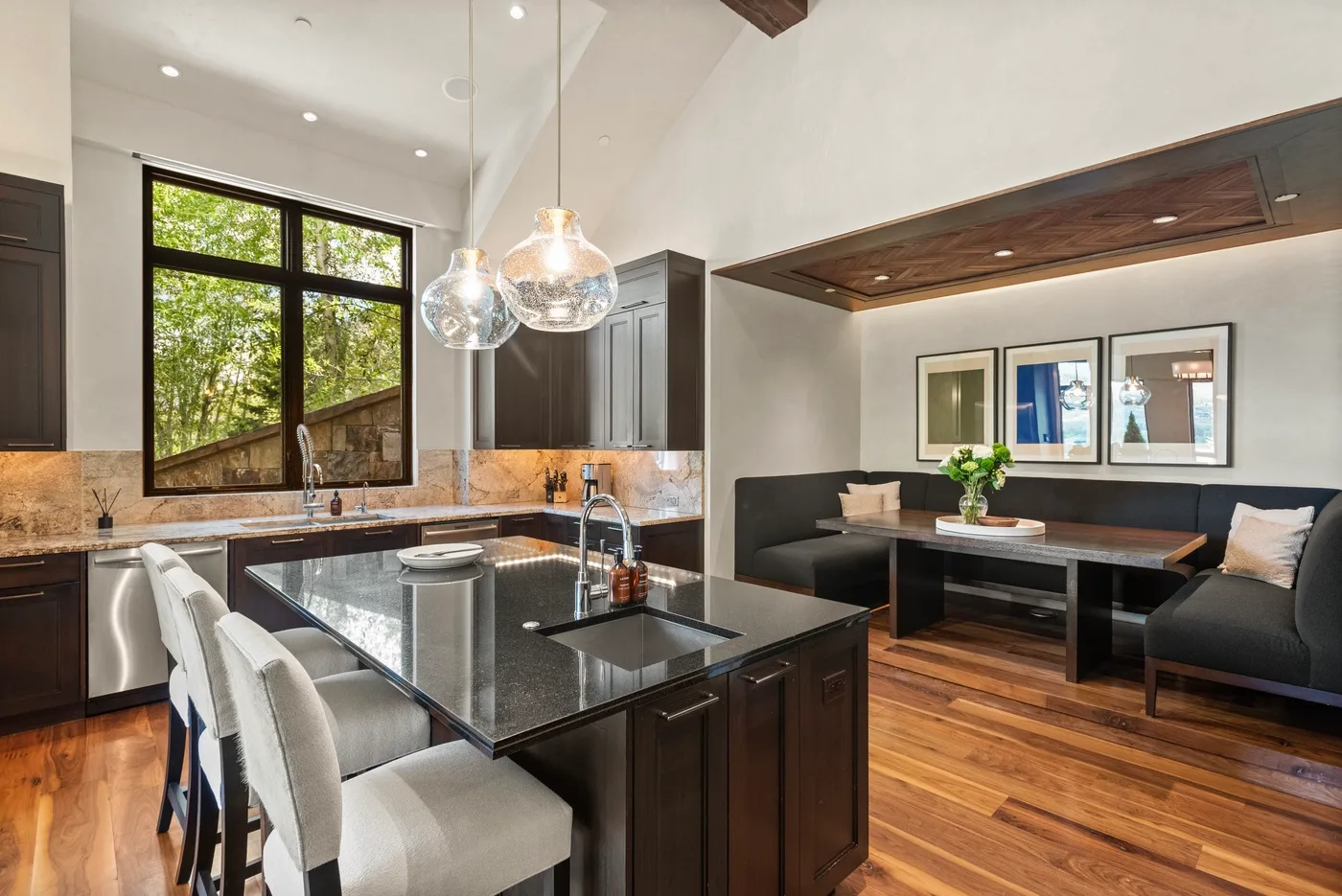 Cocina y comedor de concepto abierto con una isla oscura y asientos integrados.