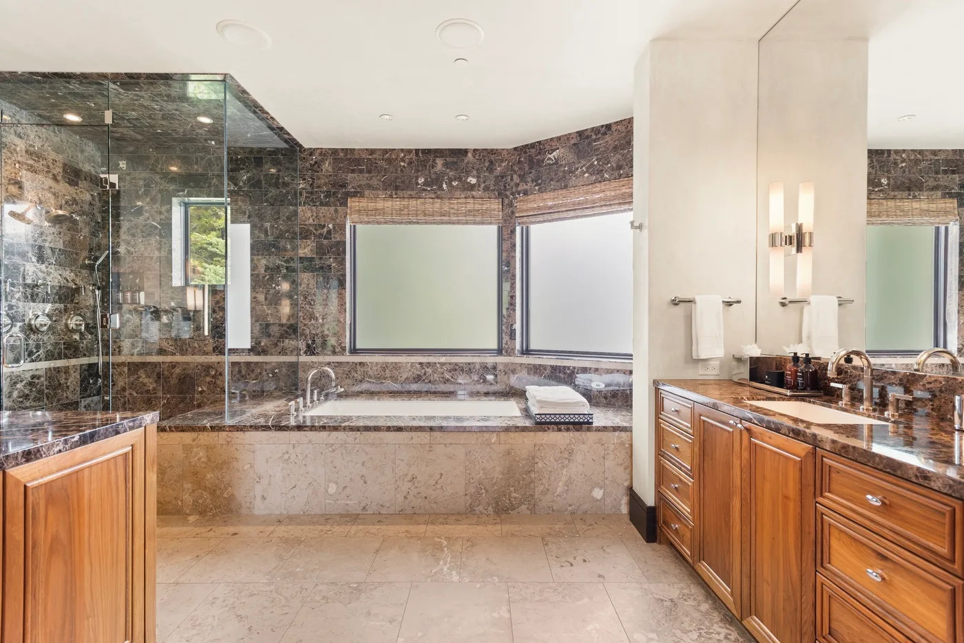 Un baño amplio con bañera, ducha de vidrio y gabinetes de madera.