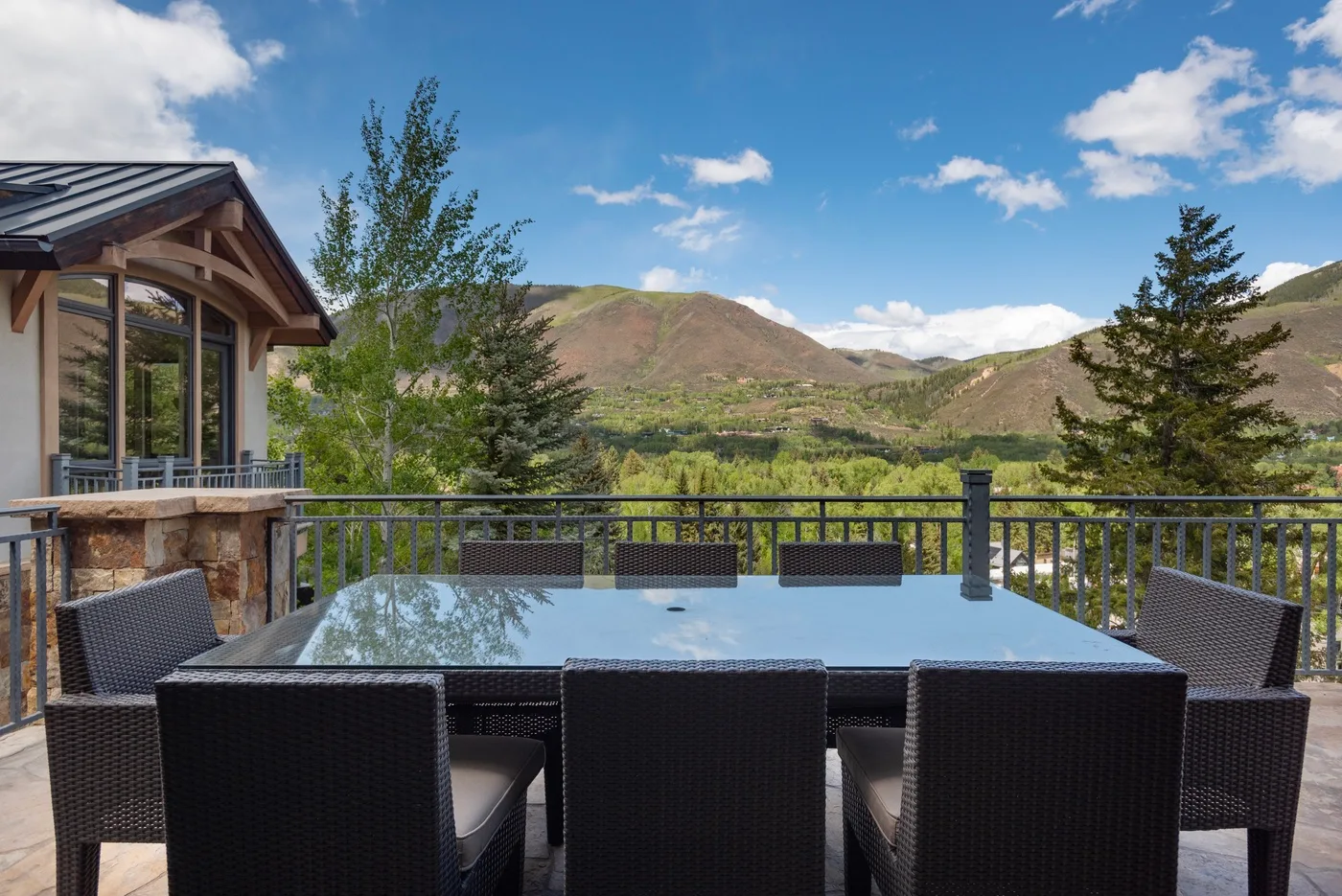 Una zona de comedor al aire libre tiene vistas a un valle montañoso.
