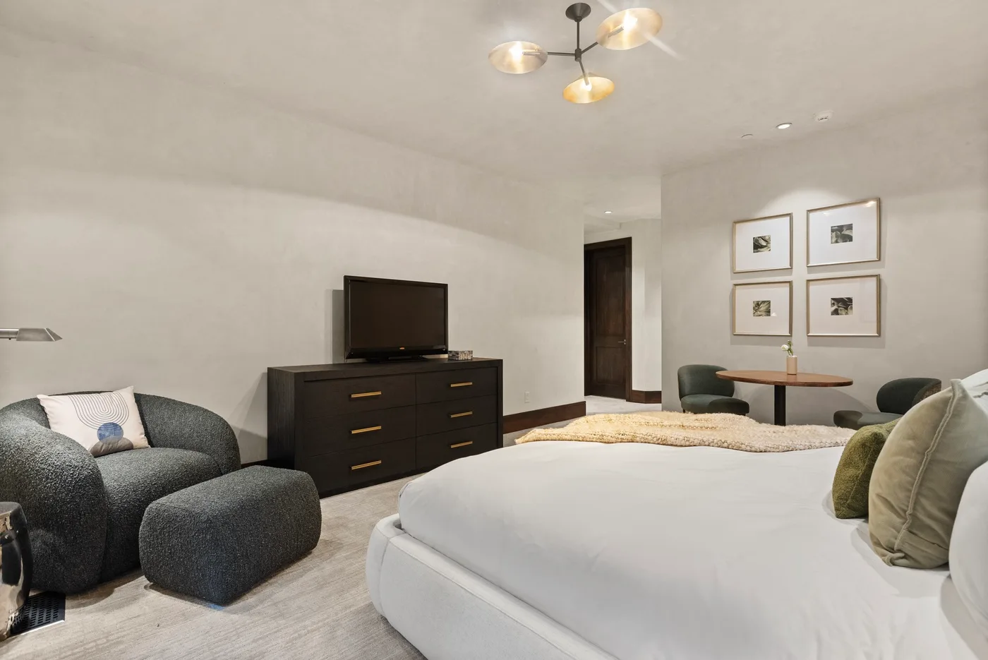 Un dormitorio con una cama grande, una cómoda oscura y una pequeña zona de estar.