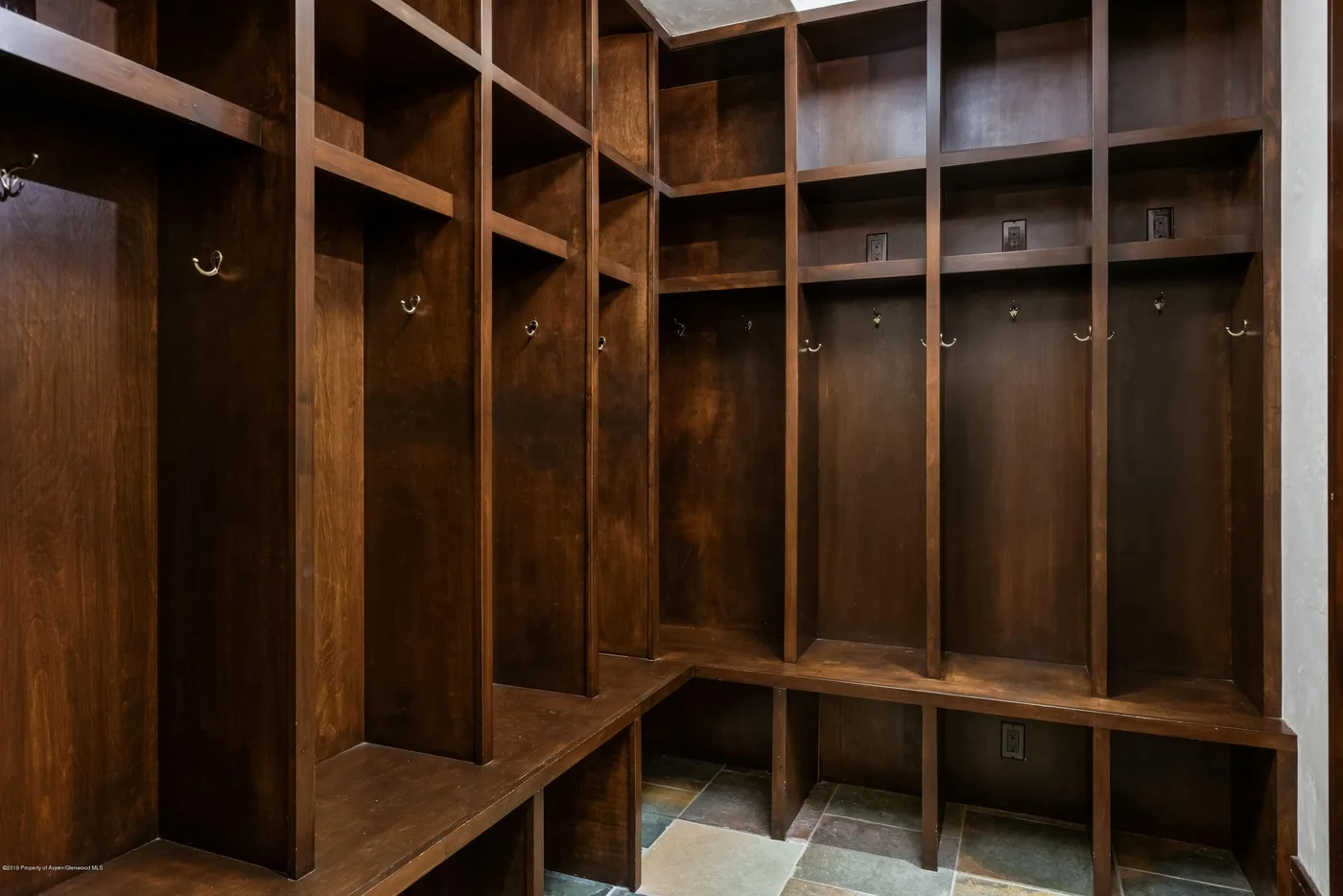 Un vestuario revestido de madera con compartimentos abiertos y ganchos.