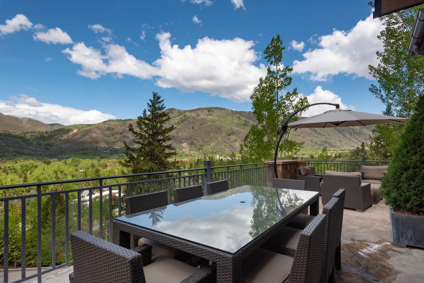 Una zona de comedor al aire libre con mesa y asientos frente a un valle verde.