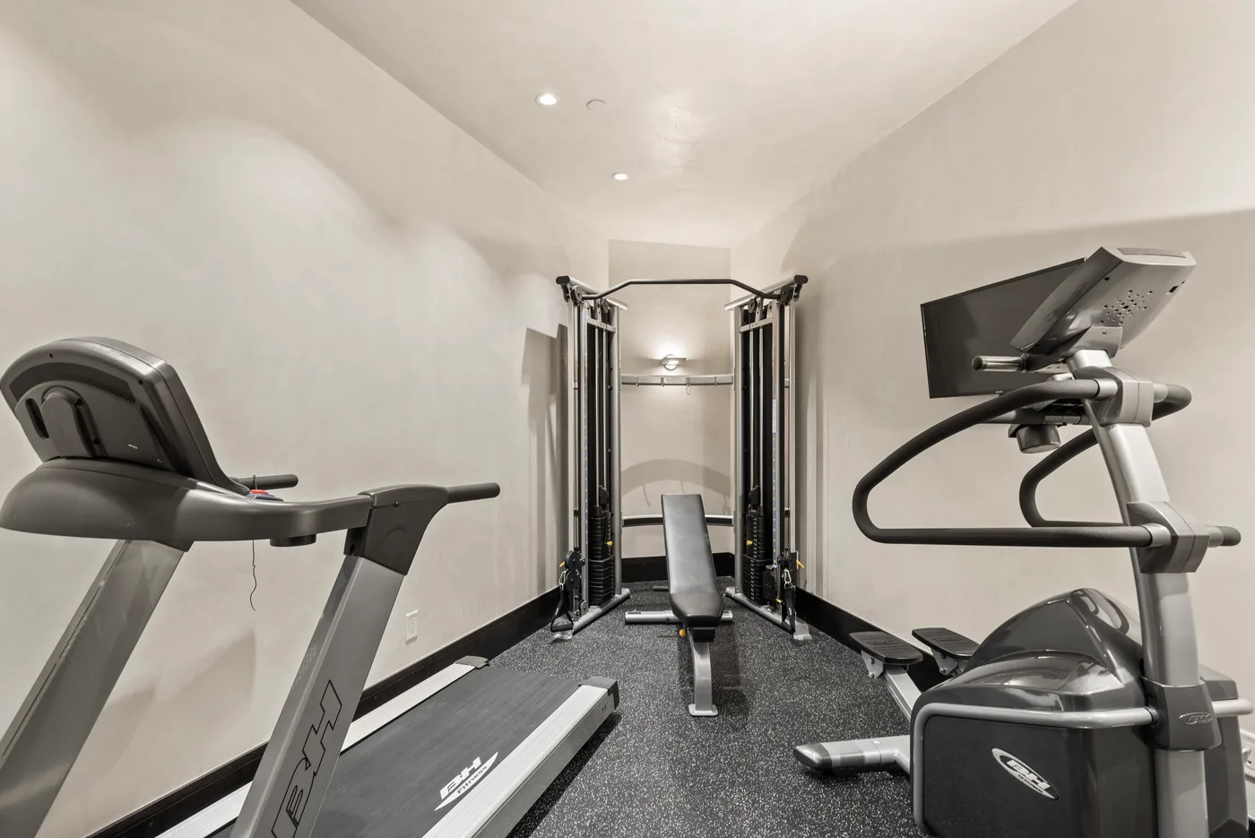 Un gimnasio compacto con máquinas de ejercicio y una estación de pesas.