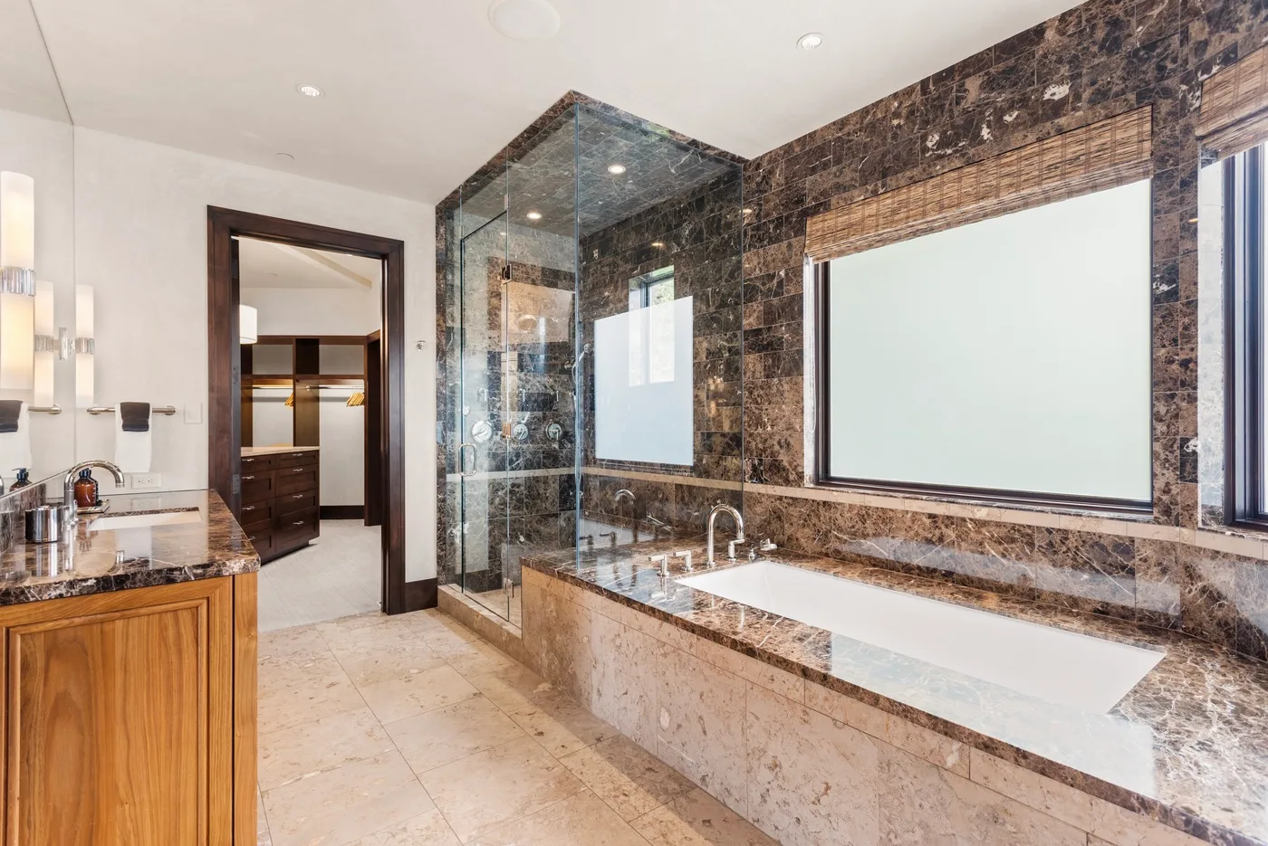Un baño espacioso cuenta con bañera, ducha de cristal y superficies de piedra oscura.