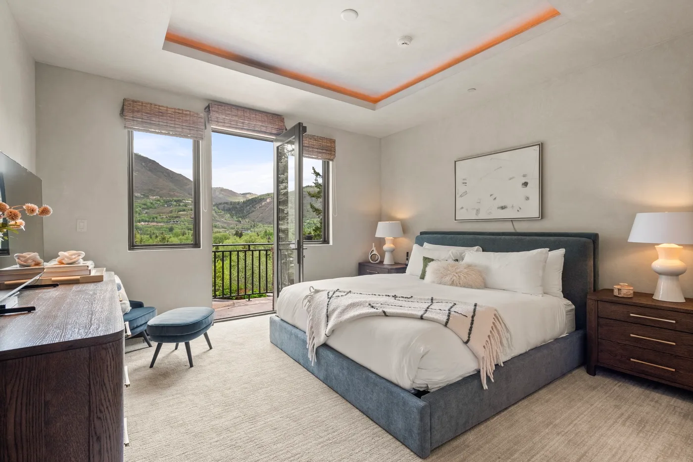 Un dormitorio con una cama grande junto a ventanas con vistas a una ladera verde.