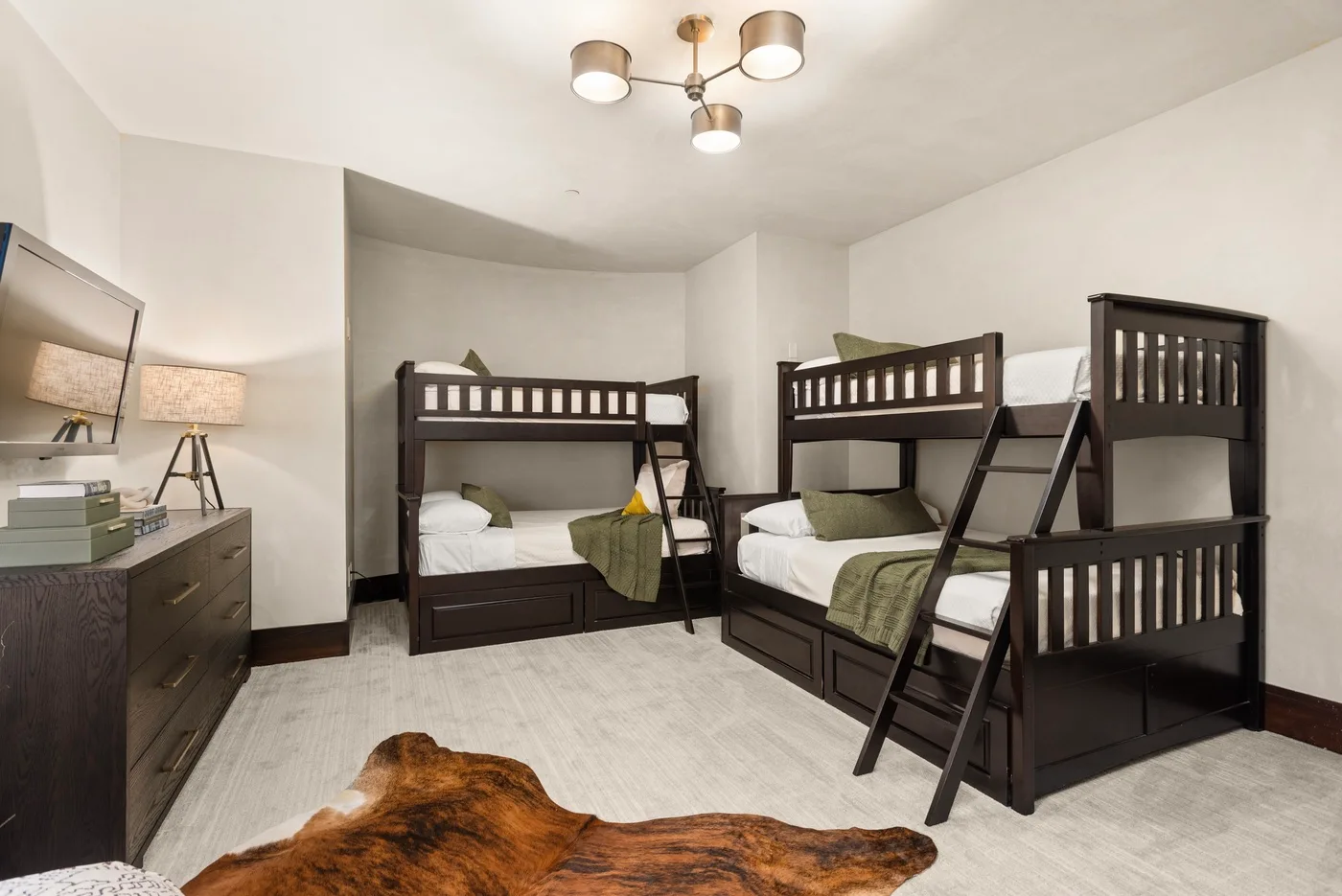 Un dormitorio con literas oscuras y ropa de cama verde.