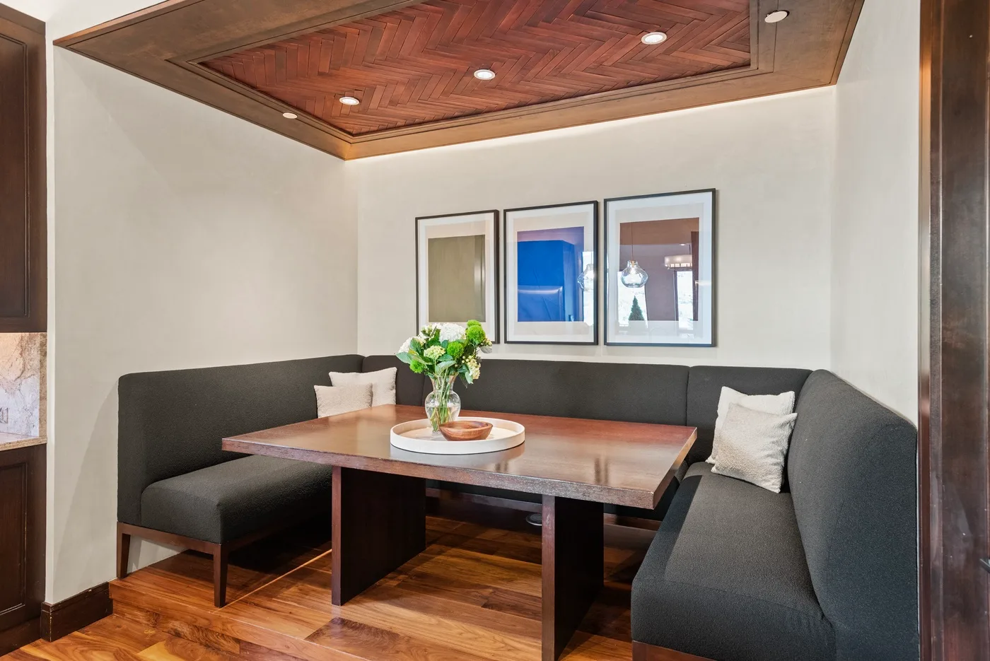 Un rincón de comedor con asientos empotrados, una mesa de madera y cuadros enmarcados.