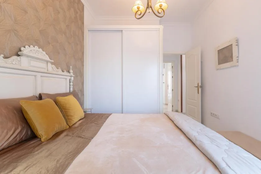 A bedroom with a bed, white wardrobe, and an open doorway.